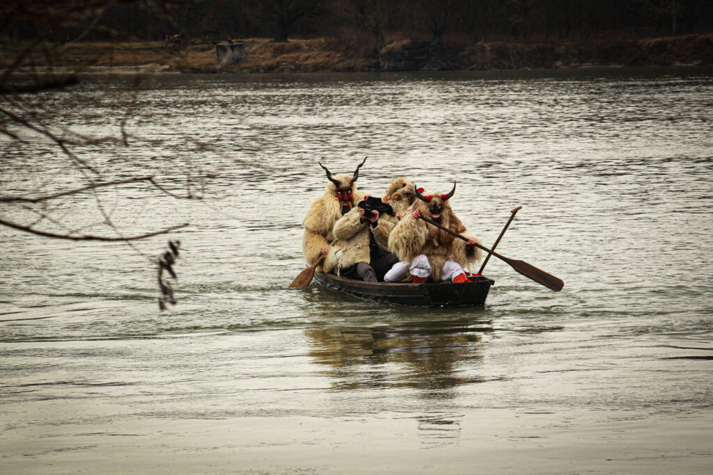 Masked men in fur outfits in a small boat on the Danube river